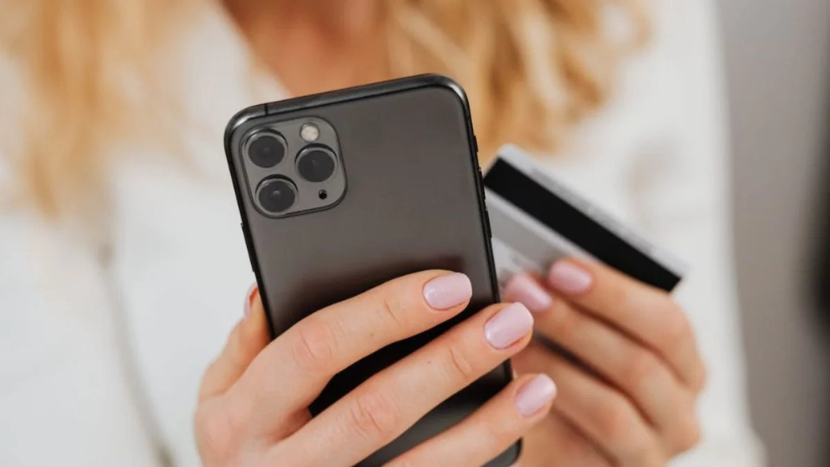 mulher segurando um cartão e o celular representando segurança digital